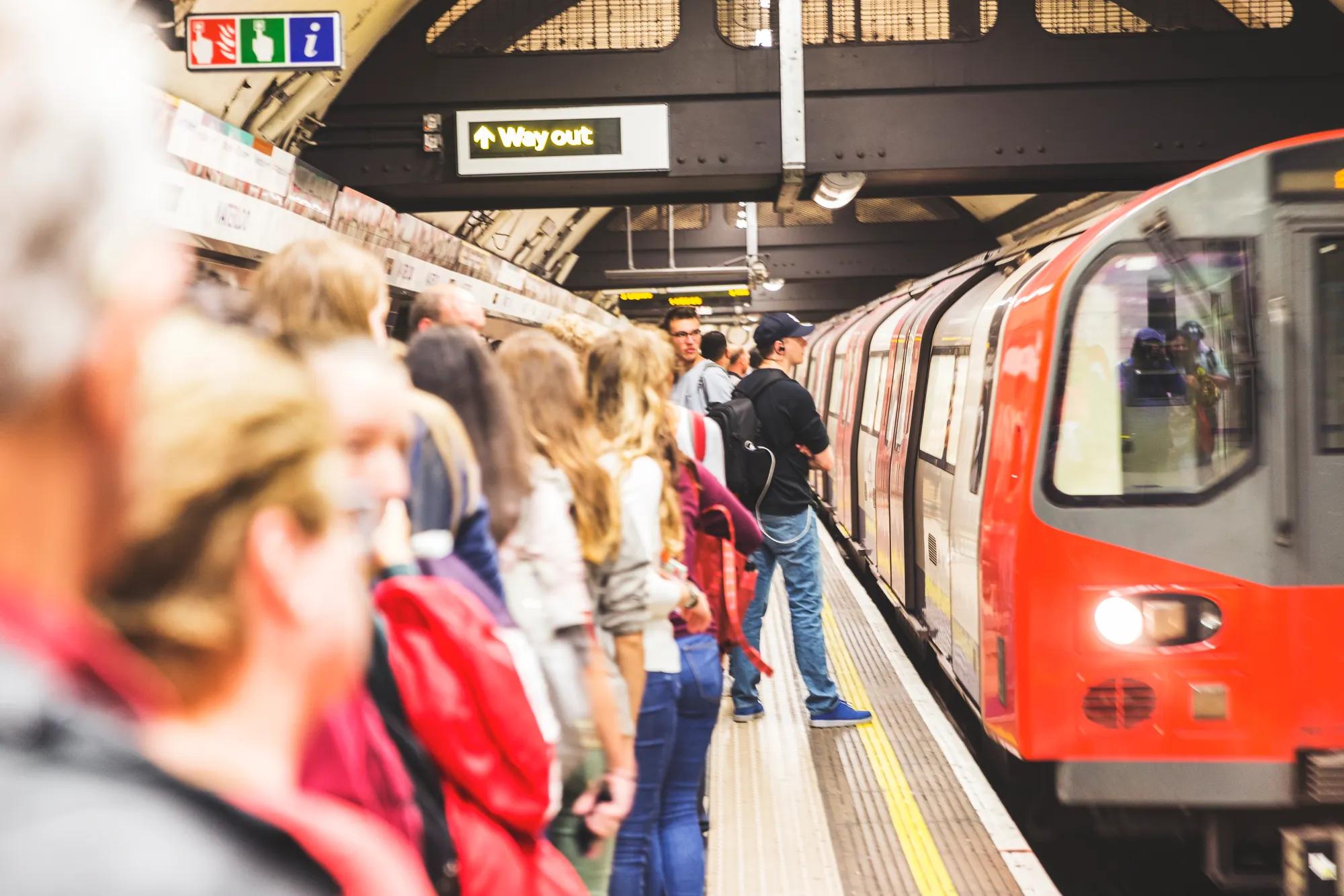 Groups of people abiding by the famous "Mind The Gap" rule and waiting for the train to slow down, giving space for people to disembark. 